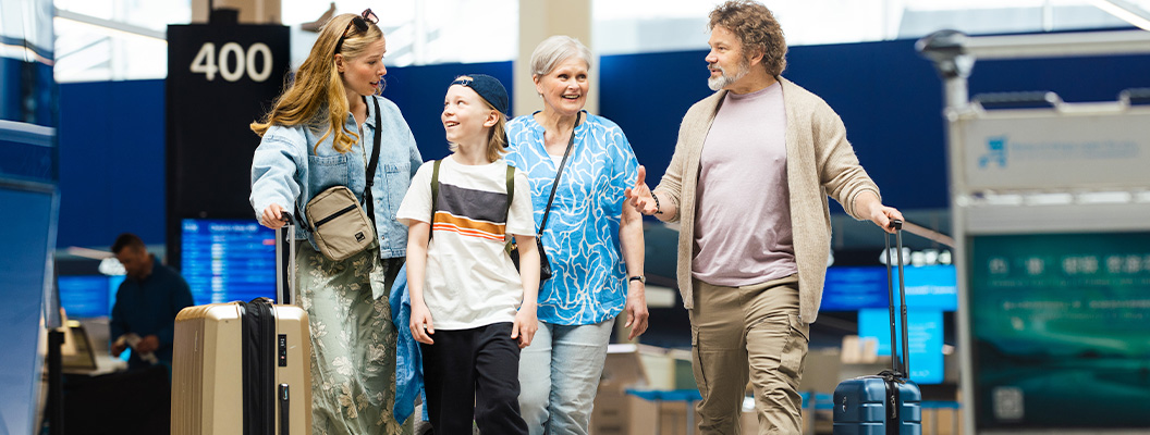 Perhe matkalaukkujen kanssa lentokentällä lähdössä matkalle
